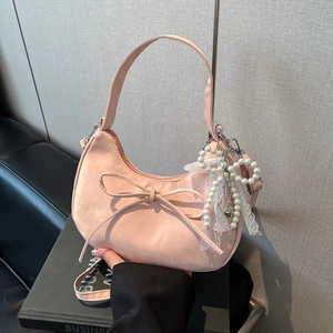 Close-up of a pink hobo bag with a bow decoration and pearl lace butterfly charm