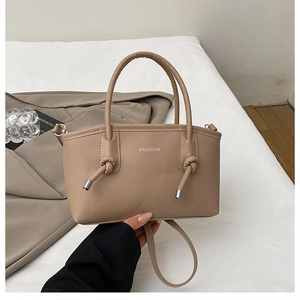 Dettaglio borsa a mano beige in ecopelle con stampa FASHION e nodi decorativi