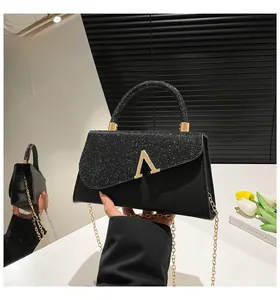 Détail du sac bandoulière noir avec texture scintillante et boucle en métal doré en V