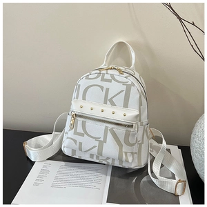 Close-up of a vintage letter-print mini backpack with gold zippers on an open magazine