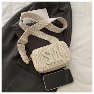 Detail der cremefarbenen Web-Umhängetasche mit SM-Logo und geometrischem breitem Gurt