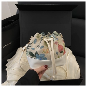 Detail of floral tapestry bucket bag with white leather trim and drawstring closure