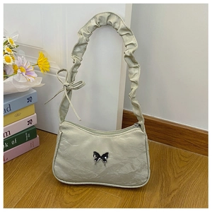 Détail du sac sous l'aisselle plissé vert pistache avec bandoulière à volants et papillon