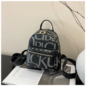 Close-up of black leather backpack with letter prints and gold rivet details