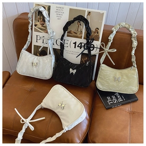 Détail de quatre sacs à bandoulière en argent, noir, vert et crème avec des papillons