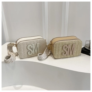 Detail von gewebten Stroh-Umhängetaschen mit SM-Logo und breiten Jacquard-Trägern