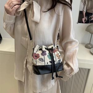 Retro drawstring bucket bag with vintage floral print and black leather base trim