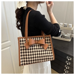 Détail du sac cabas à carreaux avec un grand nœud en cuir marron et un tissu jacquard
