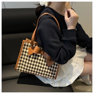 Détail du cabas tissé à damier avec un grand nœud en cuir marron porté par un mannequin