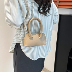 Sac dôme beige chic en cuir grainé avec bandoulière chaîne dorée porté par un mannequin