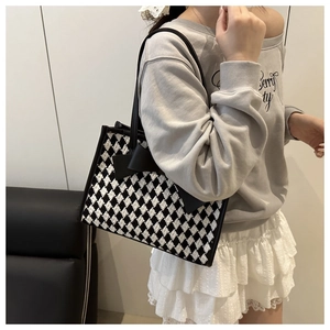 Gros plan sur un sac cabas à carreaux noir et blanc orné d'un nœud papillon en relief