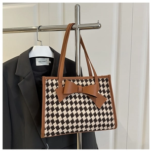 Détail du cabas à carreaux avec nœud en cuir marron et poignée élégante de sac