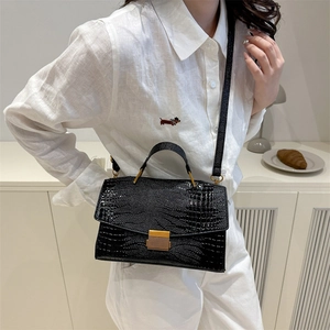 Elegante borsa a mano nera con stampa coccodrillo e chiusura dorata su una modella