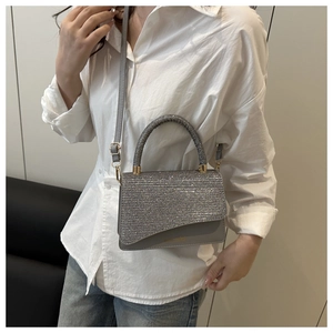 Detail of silver sequined crossbody bag with metallic logo and adjustable strap