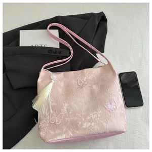 Detailed texture of pink lace tote with butterfly embroidery and beaded tassel charm