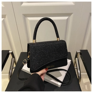 Detail of black sequined handbag with golden logo and adjustable shoulder strap