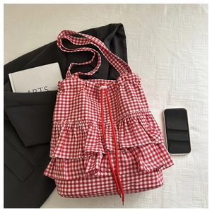 Détail du sac cabas à carreaux rouges avec triple volants et cordon sur tissu blanc