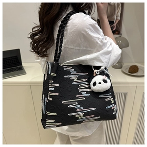 Détail d'un sac cabas noir avec broderie ondulée colorée et charmant pendentif panda