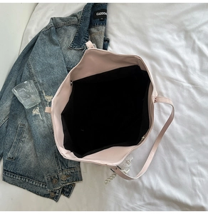 Dettaglio interno di una borsa tote rosa in pelle PU con fodera nera e ciondolo in pizzo