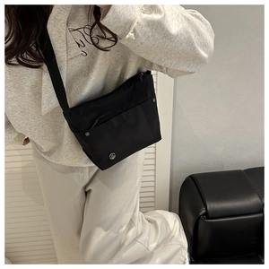 Detail view of the black nylon crossbody bag with front pocket and adjustable strap