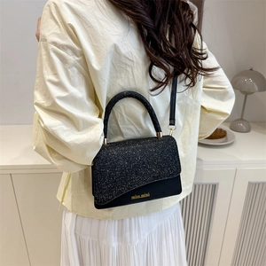 Elegant black sequin crossbody bag with gold logo shown in a lifestyle setting