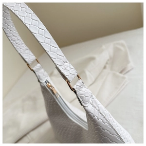 Detailed close-up of woven white leather handbag with elegant gold metal ring buckle