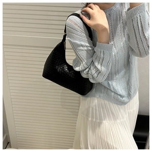 Detail of a black woven leather hobo bag with top metal zipper and minimalist strap