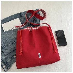 Detail of red canvas crossbody bag with red and white gingham drawstring and strap