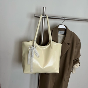 Detail of cream tote bag with pearl bow pendant and lace ribbon on a metal hanger