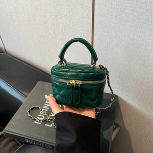Close-up of dark green quilted leather vanity case with gold zippers and chain strap