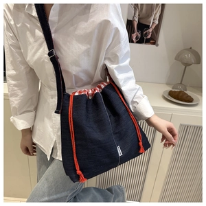 Detail of blue denim bucket bag with orange drawstring and red checkered lining detail