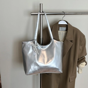 Detail of silver metallic tote bag with pearl lace bow charm on a metal hanger