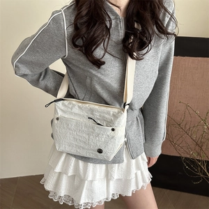 Minimalist white pleated fabric crossbody bag with wide shoulder strap and textured finish