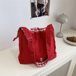 Detail view of red canvas tote bag showing gingham drawstring lining and fashion tag