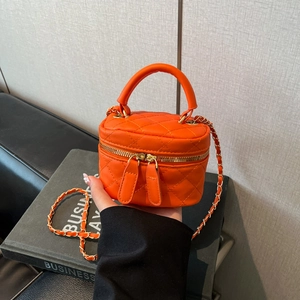 Detail of orange quilted PU leather vanity box bag with golden dual zippers and chain strap
