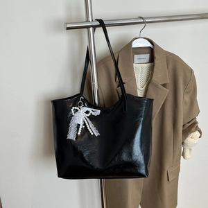 Borsa tote in pelle nera lucida con elegante ciondolo a fiocco di pizzo e perle