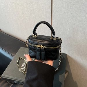 Detail of black quilted leather mini box bag with chain strap and double zipper closure