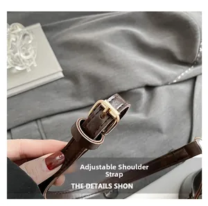 Close-up of adjustable dark brown leather shoulder strap with golden metal pin buckle detail