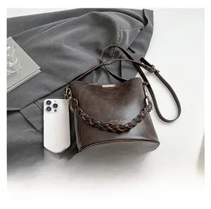 Detailed top view of retro dark brown bucket bag with woven handle and phone for scale