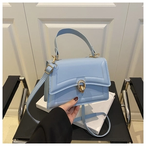 Dettaglio ravvicinato della borsa in pelle azzurra con elegante chiusura a scatto dorata