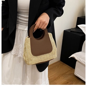 Detail of hand-woven straw tote bag with brown leather trim and round cutout handles