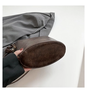 Detailed macro view of dark brown leather bucket bag base with fine stitching and hardware