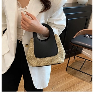 Detail of vintage contrast patchwork straw handbag with black leather handle and woven texture