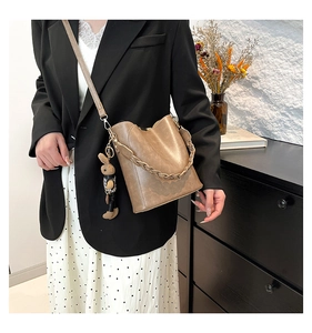Retro brown leather bucket bag shown on model with woven strap and rabbit charm