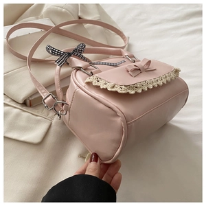 Close-up of pink handbag featuring white lace trim, small bow, and checkered ribbon handle