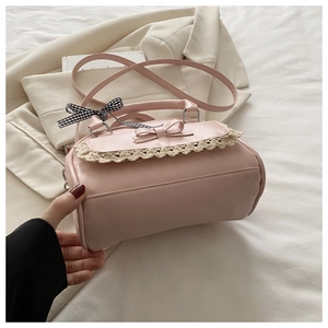 Detailed shot of pink handbag featuring lace trim, a 3D bow, and checkered ribbon accessory
