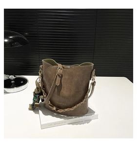 Detail of brown vintage bucket bag with woven chain strap and cute bear charm