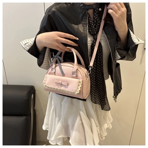 Close-up of pink PU leather handbag featuring lace trim, bow, and checkered ribbon charm