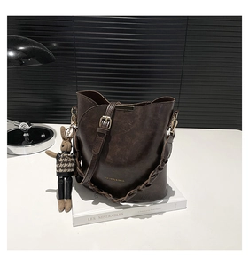 Detail of dark brown retro bucket bag with woven handle and cute rabbit charm on a book
