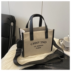 Detail of beige canvas tote with black leather trim and chic Paris logo printing